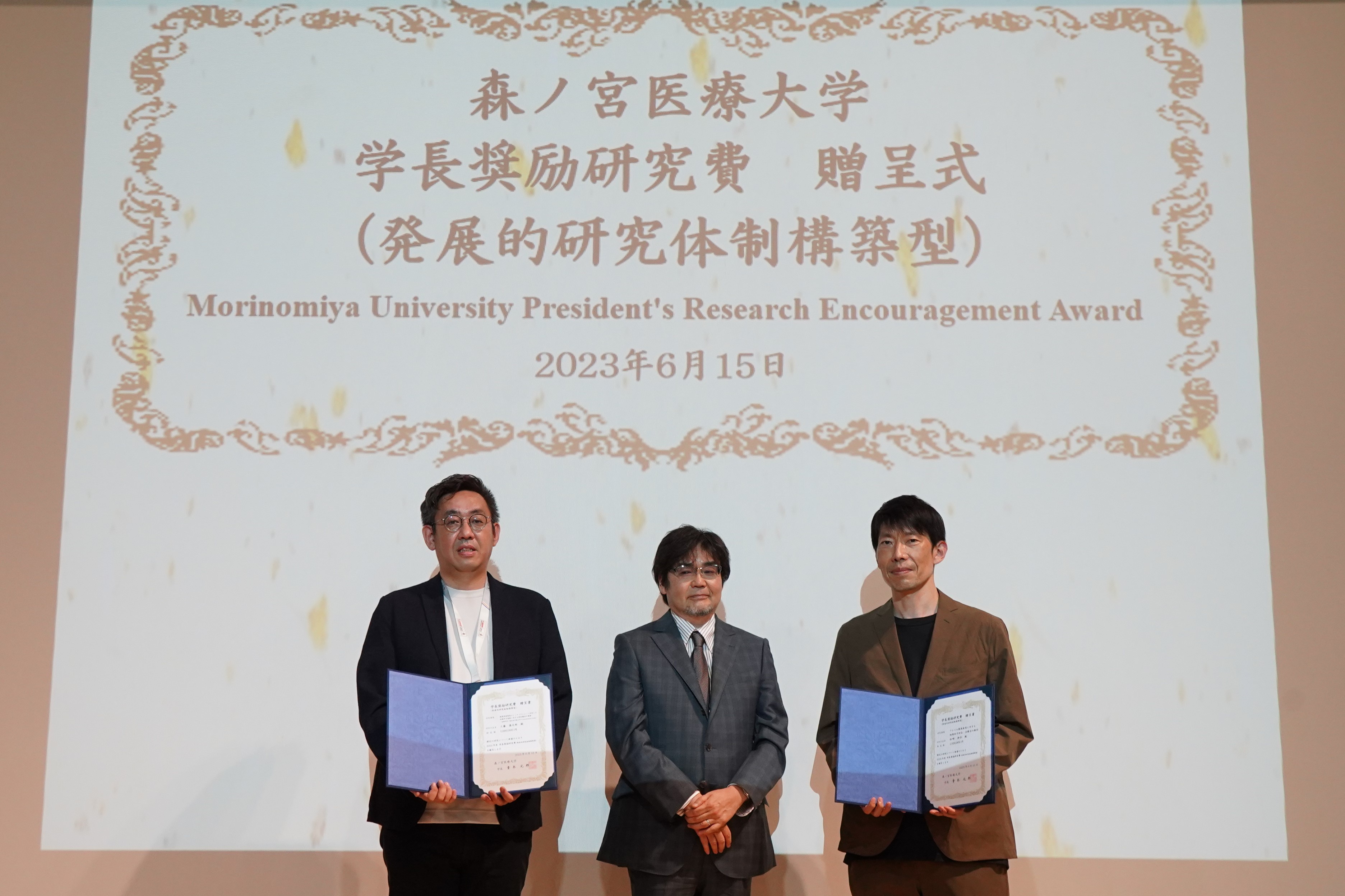 青木元邦学長より研究チームを代表して工藤慎太郎教授と中原英博教授へ学長奨励研究費が贈呈されました。